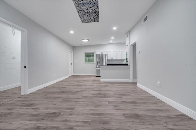 unfurnished living room with vaulted ceiling and light wood-type flooring