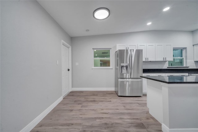 kitchen with light wood-type flooring, backsplash, stainless steel fridge with ice dispenser, lofted ceiling, and white cabinets