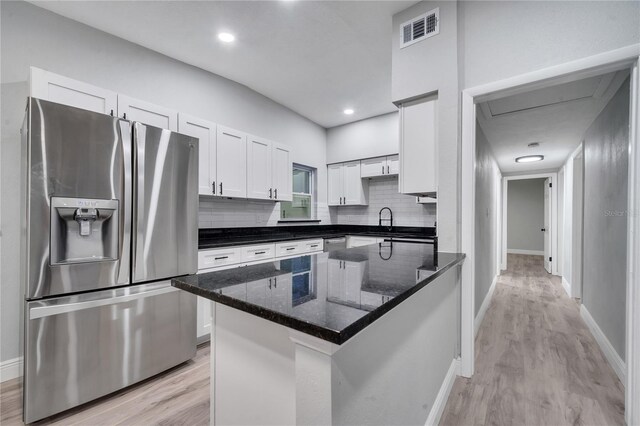 kitchen with dark stone countertops, light hardwood / wood-style flooring, decorative backsplash, stainless steel refrigerator with ice dispenser, and white cabinets