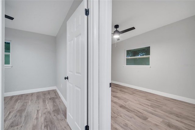 interior space with a ceiling fan, baseboards, vaulted ceiling, and wood finished floors