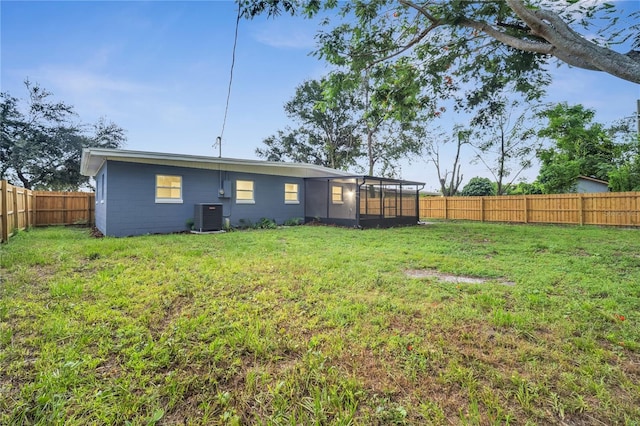 rear view of property featuring a lawn and central air condition unit