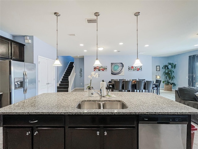 kitchen with appliances with stainless steel finishes, sink, an island with sink, and decorative light fixtures