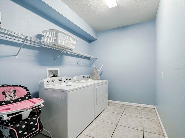 clothes washing area featuring independent washer and dryer, a textured ceiling, and light tile patterned floors