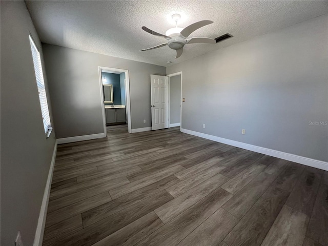 unfurnished room with ceiling fan, a textured ceiling, dark wood-style flooring, visible vents, and baseboards