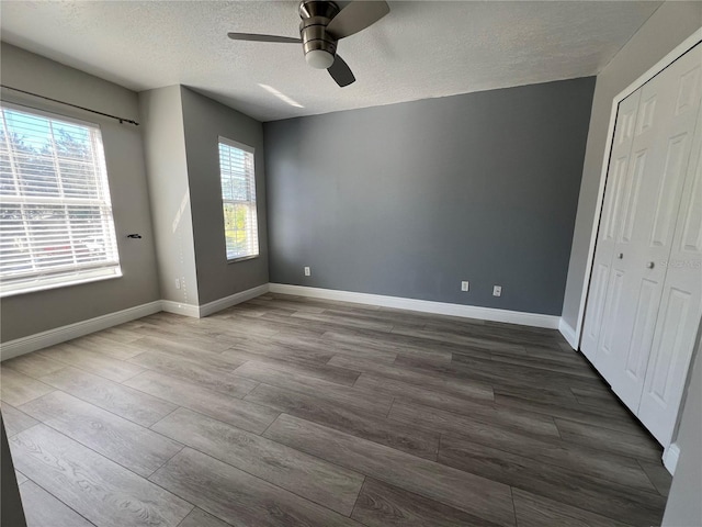 unfurnished bedroom with baseboards, dark wood finished floors, and a textured ceiling