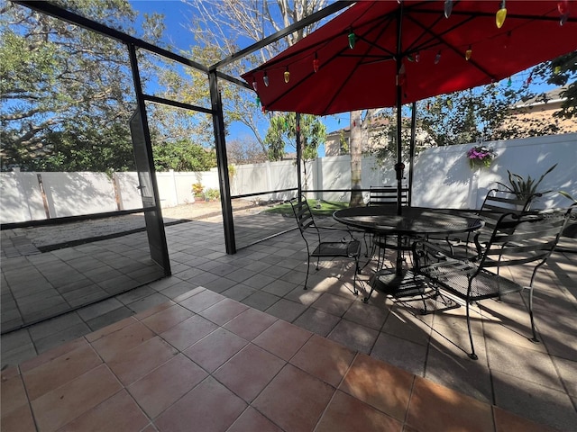 view of patio featuring outdoor dining area, glass enclosure, and a fenced backyard