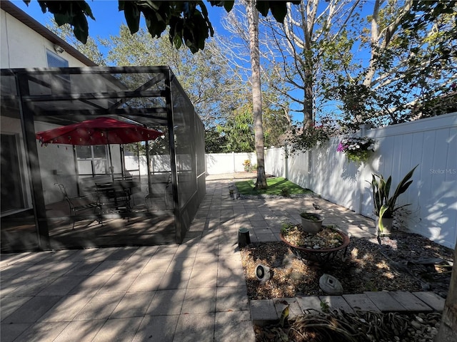 view of yard featuring glass enclosure, a fenced backyard, and a patio