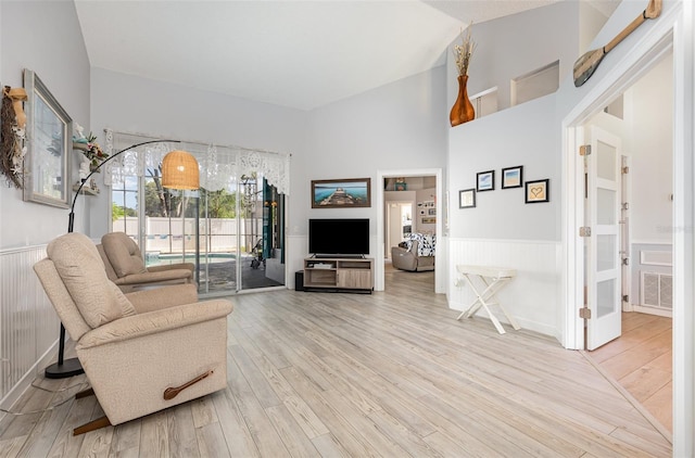 living room featuring a towering ceiling and light hardwood / wood-style flooring