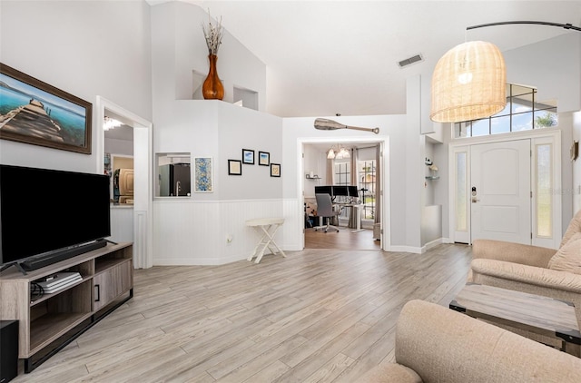 living room featuring a high ceiling and light hardwood / wood-style floors