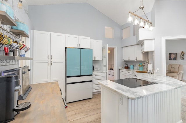 kitchen featuring light wood-type flooring, refrigerator, black electric cooktop, kitchen peninsula, and high vaulted ceiling