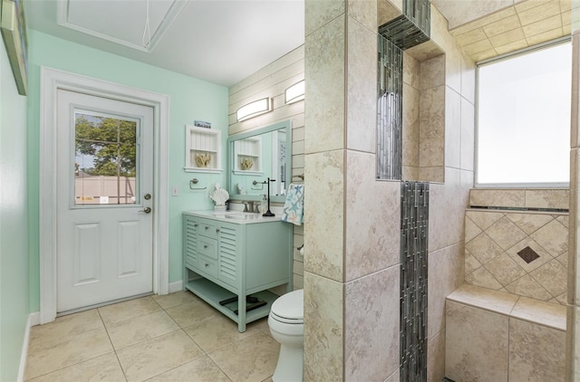 bathroom with vanity, toilet, a tile shower, and tile patterned floors