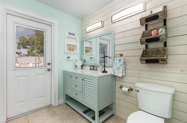 bathroom with wood walls, tile patterned flooring, toilet, and vanity