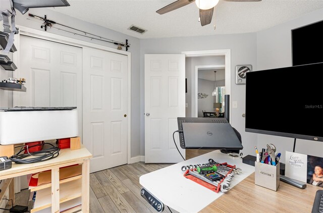 office space featuring a textured ceiling, ceiling fan, and light hardwood / wood-style floors