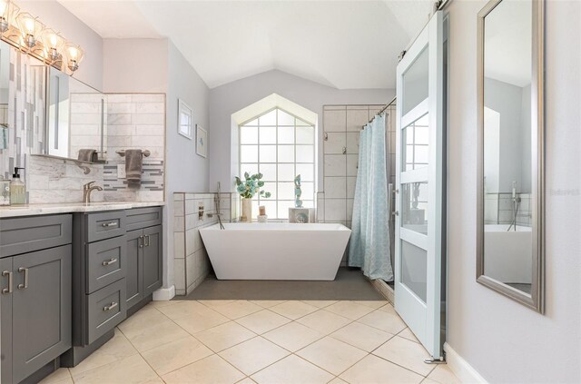 bathroom with tile patterned flooring, vanity, vaulted ceiling, tile walls, and shower with separate bathtub