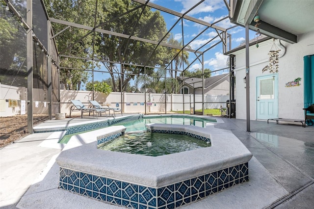 exterior space with glass enclosure, an in ground hot tub, and a patio