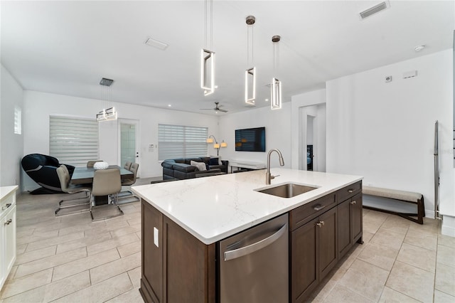 kitchen featuring light stone countertops, sink, pendant lighting, a kitchen island with sink, and stainless steel dishwasher