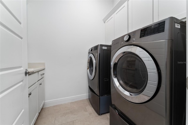 washroom with light tile patterned floors, cabinets, and washing machine and dryer