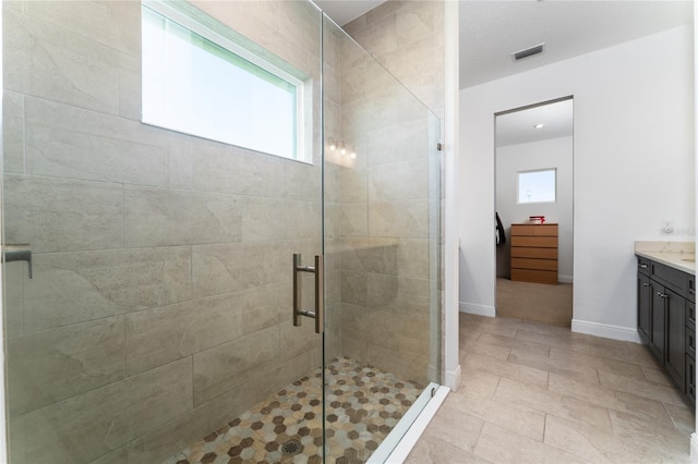 bathroom with tile patterned floors, a shower with door, and vanity