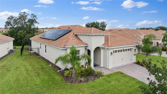 view of front facade featuring solar panels, central AC unit, a garage, and a front lawn