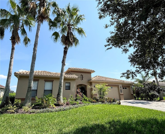 mediterranean / spanish-style house featuring a garage and a front lawn