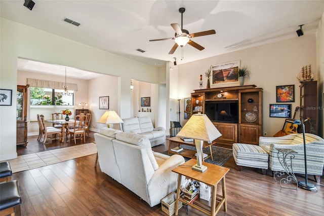 living room with ceiling fan with notable chandelier and dark hardwood / wood-style flooring