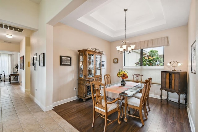 tiled dining space with a tray ceiling and a chandelier