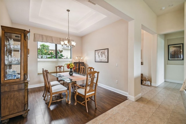 tiled dining room featuring a chandelier and a tray ceiling