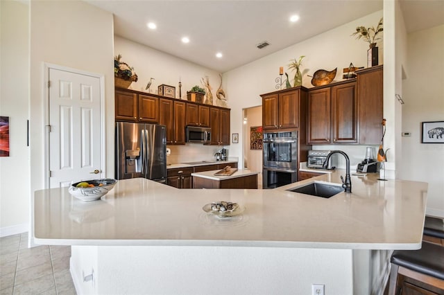 kitchen featuring a kitchen breakfast bar, kitchen peninsula, sink, appliances with stainless steel finishes, and light tile patterned flooring