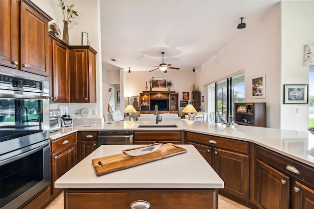 kitchen with light tile patterned floors, stainless steel appliances, sink, ceiling fan, and a kitchen island