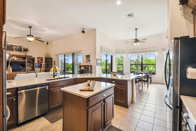 kitchen with appliances with stainless steel finishes, a kitchen island, sink, and light tile patterned flooring