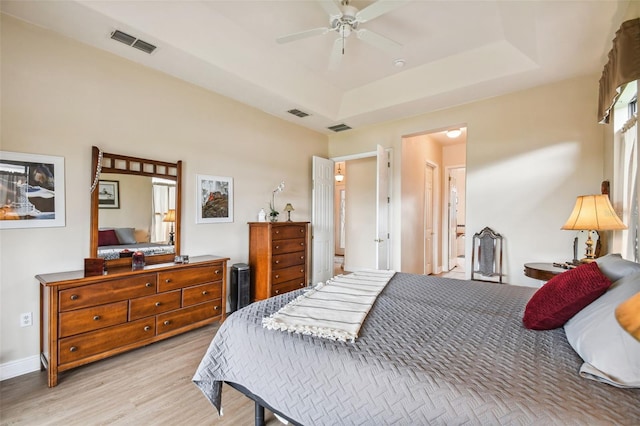 bedroom featuring a raised ceiling, light hardwood / wood-style flooring, and ceiling fan