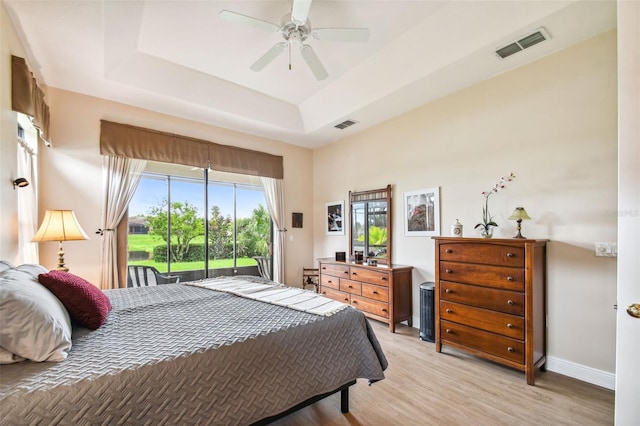 bedroom with a tray ceiling, access to outside, ceiling fan, and light hardwood / wood-style floors