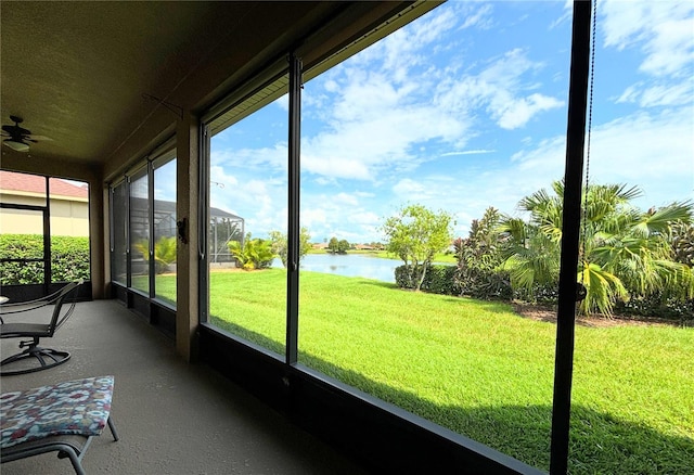 unfurnished sunroom featuring a wealth of natural light, ceiling fan, and a water view