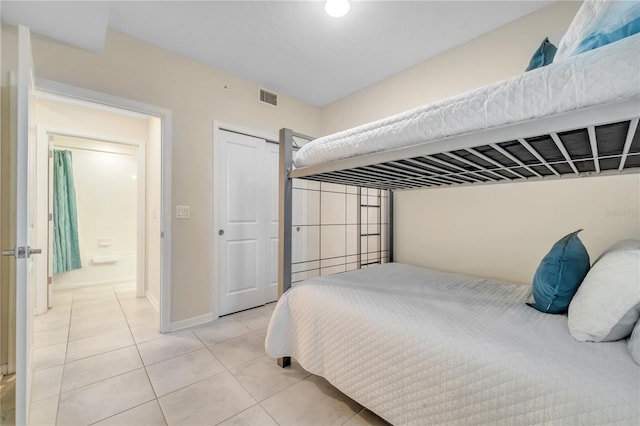 bedroom with light tile patterned floors, a closet, visible vents, and baseboards