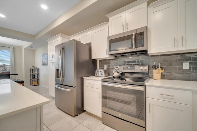 kitchen with light tile patterned floors, light countertops, decorative backsplash, appliances with stainless steel finishes, and white cabinets