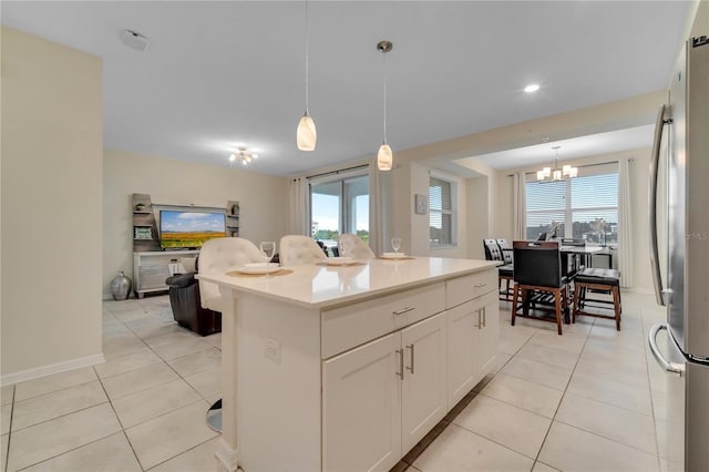 kitchen with light tile patterned floors, a kitchen island, freestanding refrigerator, and decorative light fixtures