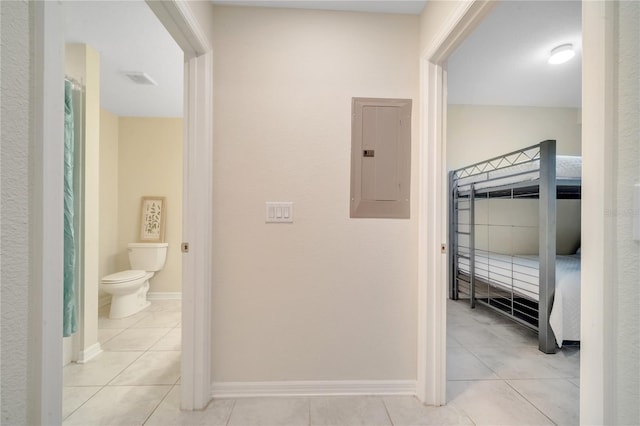 corridor with tile patterned flooring, electric panel, and baseboards