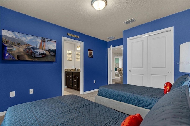 bedroom featuring ensuite bath, a textured ceiling, light colored carpet, and a closet