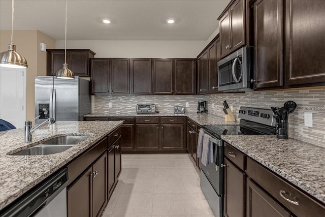 kitchen featuring tasteful backsplash, hanging light fixtures, stainless steel appliances, sink, and light stone counters