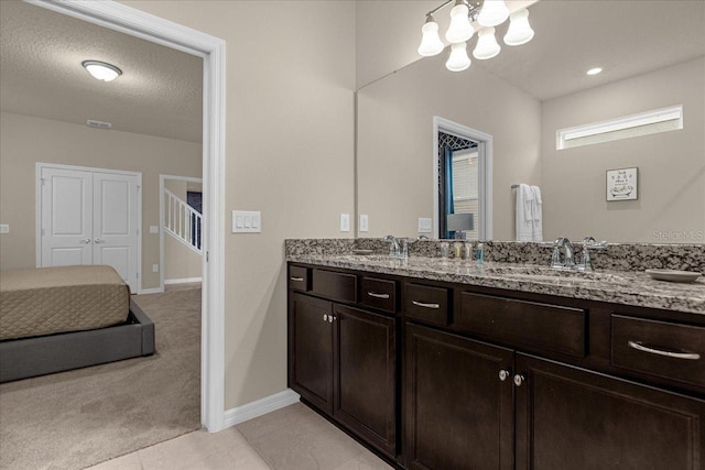 bathroom with a textured ceiling, vanity, an inviting chandelier, and tile patterned floors