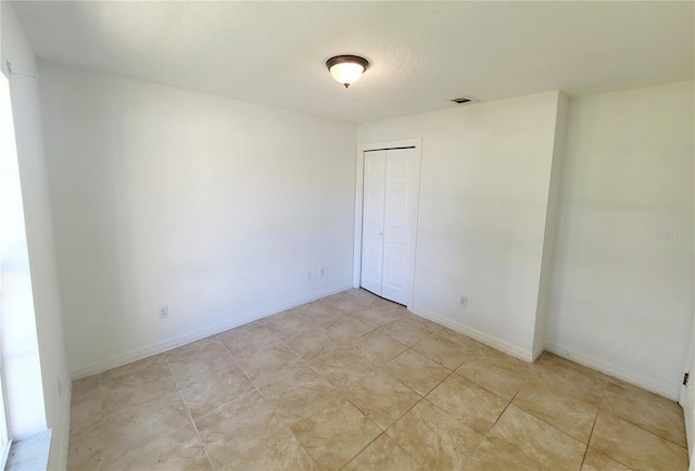 unfurnished room with baseboards, visible vents, and a textured ceiling