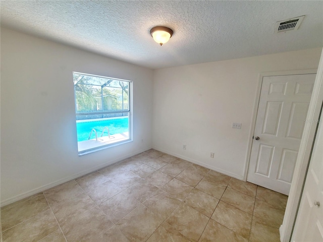 empty room with baseboards, visible vents, and a textured ceiling