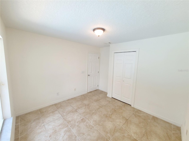 unfurnished bedroom featuring a textured ceiling, a closet, visible vents, and baseboards