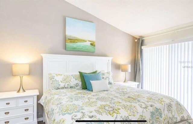 bedroom featuring multiple windows and lofted ceiling