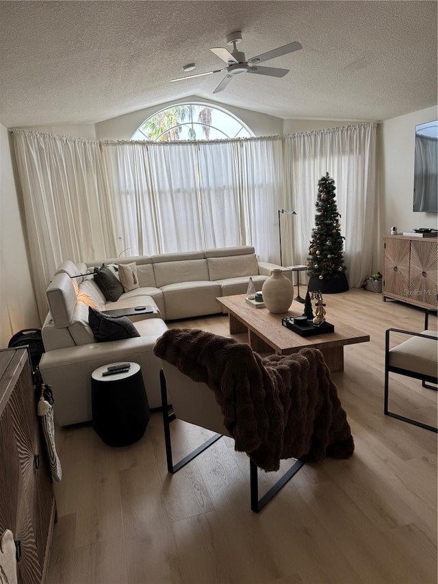 living room featuring ceiling fan, light hardwood / wood-style floors, a textured ceiling, and vaulted ceiling