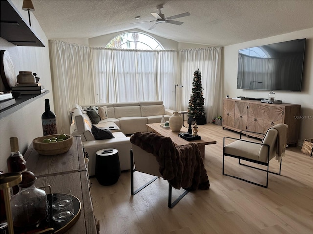 living room featuring a textured ceiling, ceiling fan, light hardwood / wood-style floors, and lofted ceiling