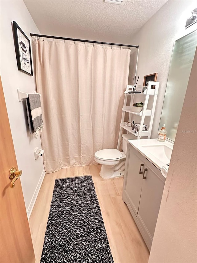 bathroom with curtained shower, a textured ceiling, toilet, vanity, and hardwood / wood-style flooring