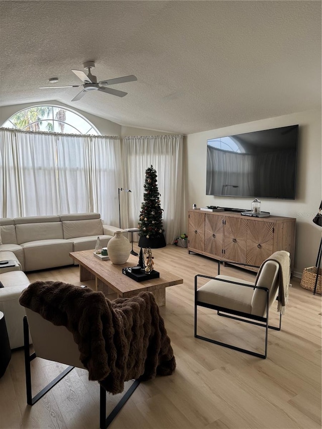 living room featuring hardwood / wood-style floors, a textured ceiling, vaulted ceiling, and ceiling fan