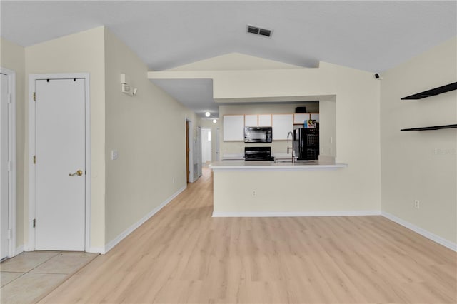 unfurnished living room with lofted ceiling, visible vents, a sink, light wood-type flooring, and baseboards