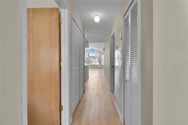hall featuring baseboards and light wood-style flooring